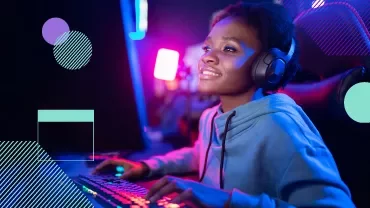 Persona sonriendo mientras juega en una computadora con luces brillantes.