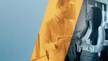 Dos personas sonrientes conversan en una oficina moderna.