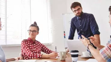 Grupo de personas discutiendo alrededor de una mesa en una oficina.