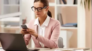 Persona revisando su teléfono en una oficina moderna.