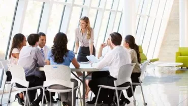 Reunión de negocios en una sala con ventanas grandes.
