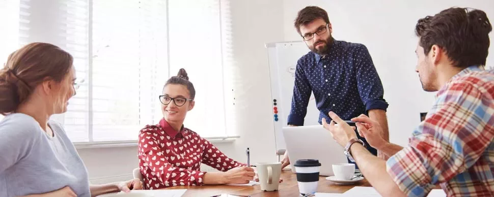 Grupo de personas discutiendo alrededor de una mesa en una oficina.