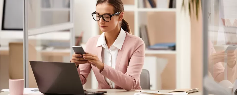 Persona revisando su teléfono en una oficina moderna.