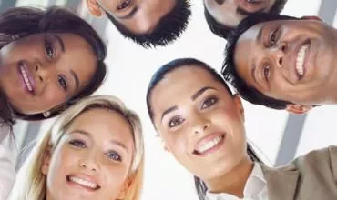 Grupo de personas sonrientes mirando hacia abajo en círculo.