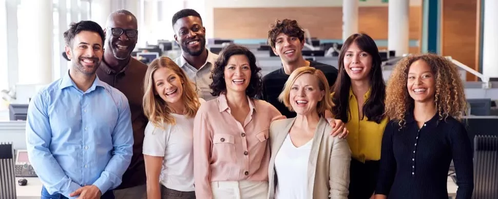 Grupo de personas en una oficina, todas sonriendo.